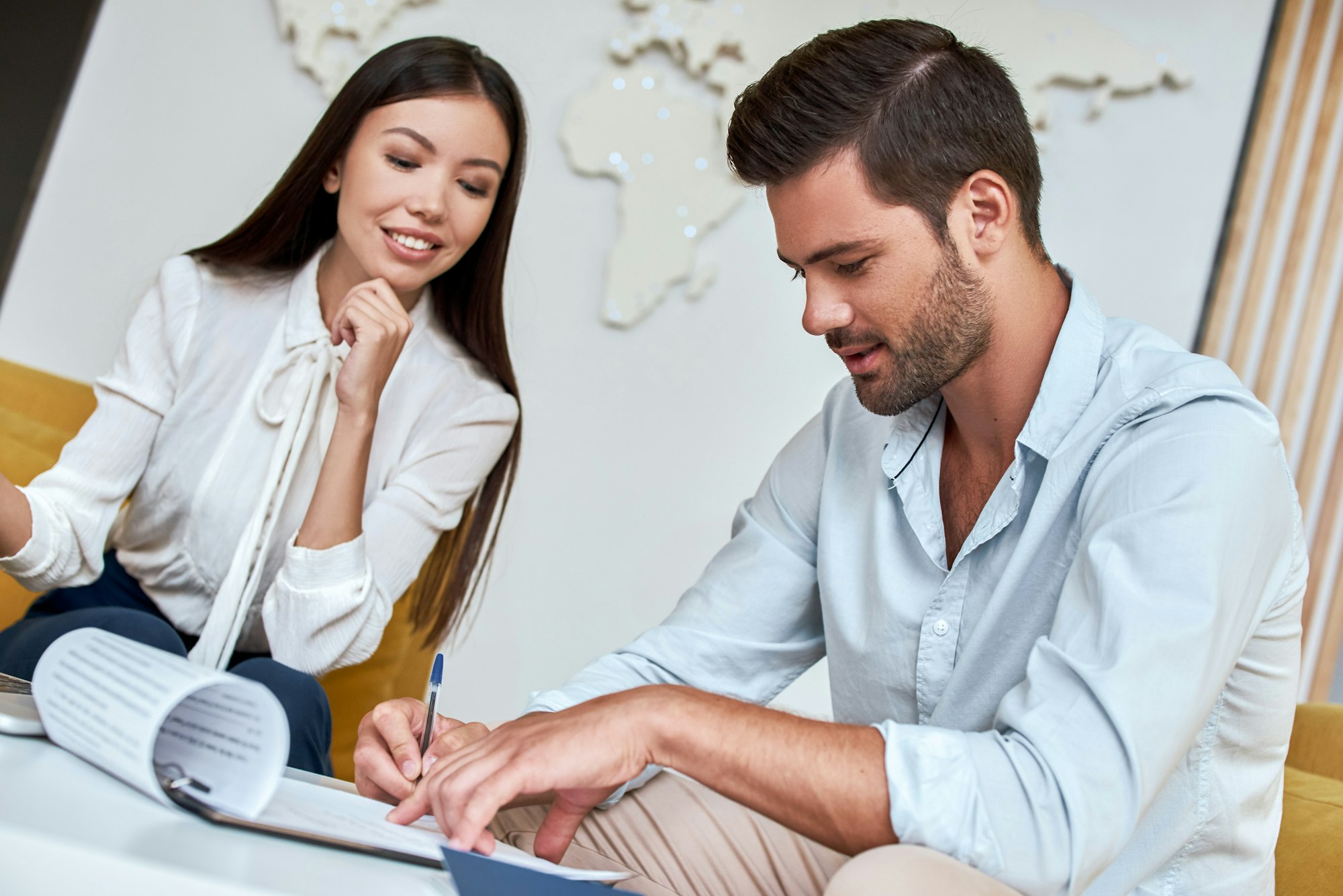 Young man signing contract for a trip with agent at the travel agency office
